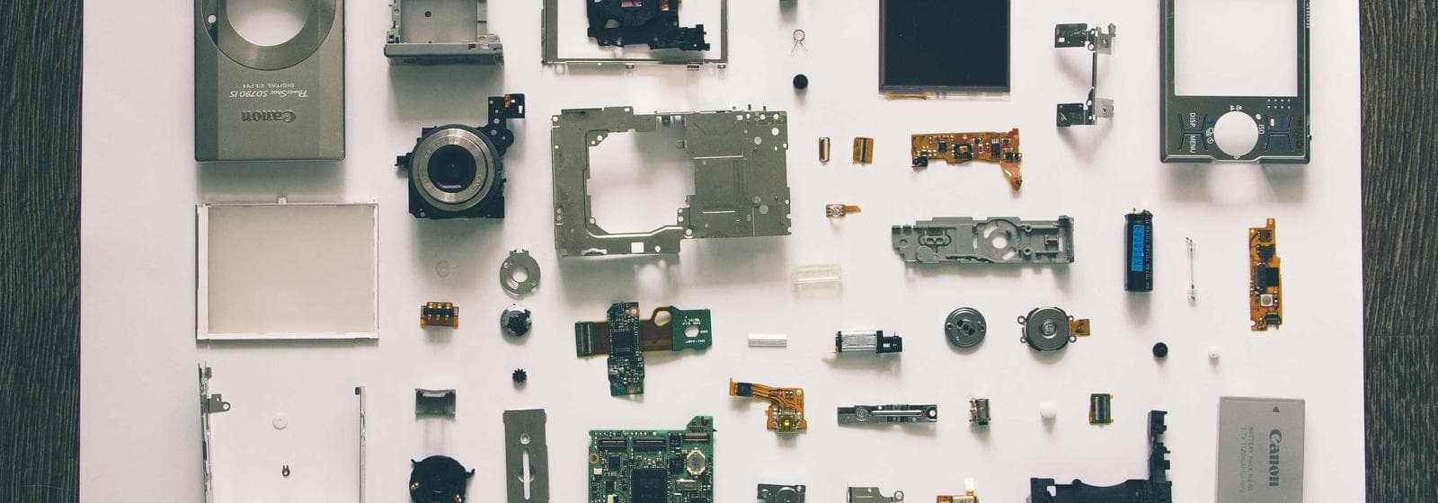A mobile phone taken apart, every component laid out in an ordered grid on a white surface.